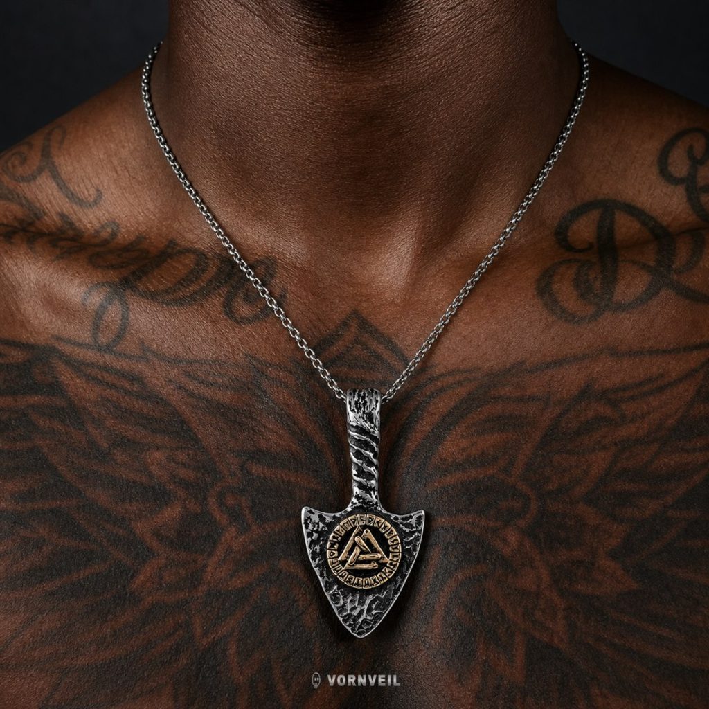 AI-assisted close worn image showing the Viking rune arrowhead pendant necklace on a tattooed chest with silver logo watermark